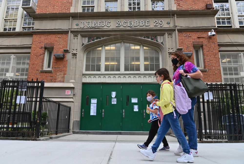 (FILES) In this file photo students walk past a public school on October 5, 2020 in the Brooklyn Borough of New York City. New York's public schools will close temporarily to combat a rise in coronavirus cases, its mayor announced on November 18, 2020, de