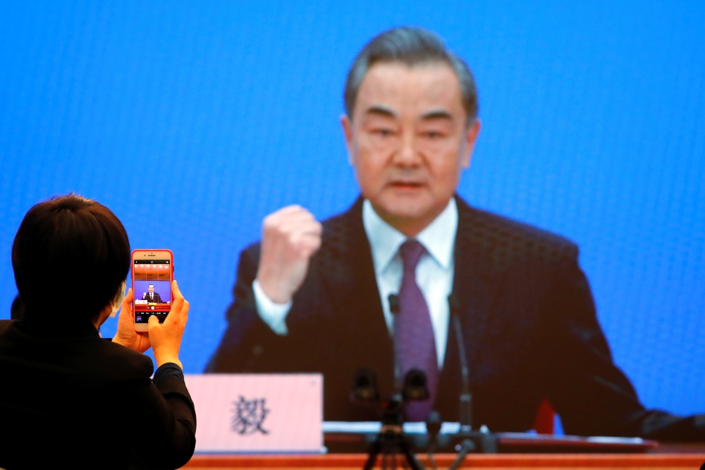 Chinese State Councillor and Foreign Minister Wang Yi is displayed on a screen as he attends via video link a news conference on the sidelines of the National People's Congress (NPC), in Beijing, China March 7, 2021. REUTERS/Thomas Peter