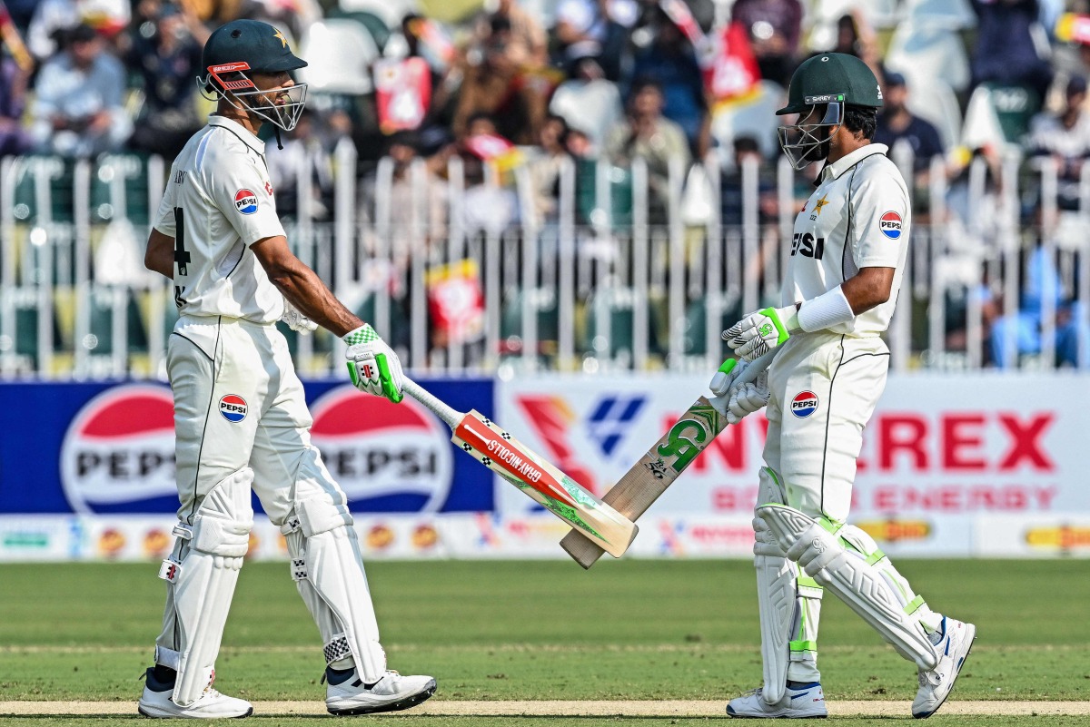 Pakistan's captain Shan Masood (L) and his teammate Babar Azam bump their bats during the first day of the second Test cricket match between Pakistan and South Africa at the Rawalpindi Cricket Stadium in Rawalpindi on October 20, 2025. (Photo by Aamir QURESHI / AFP)